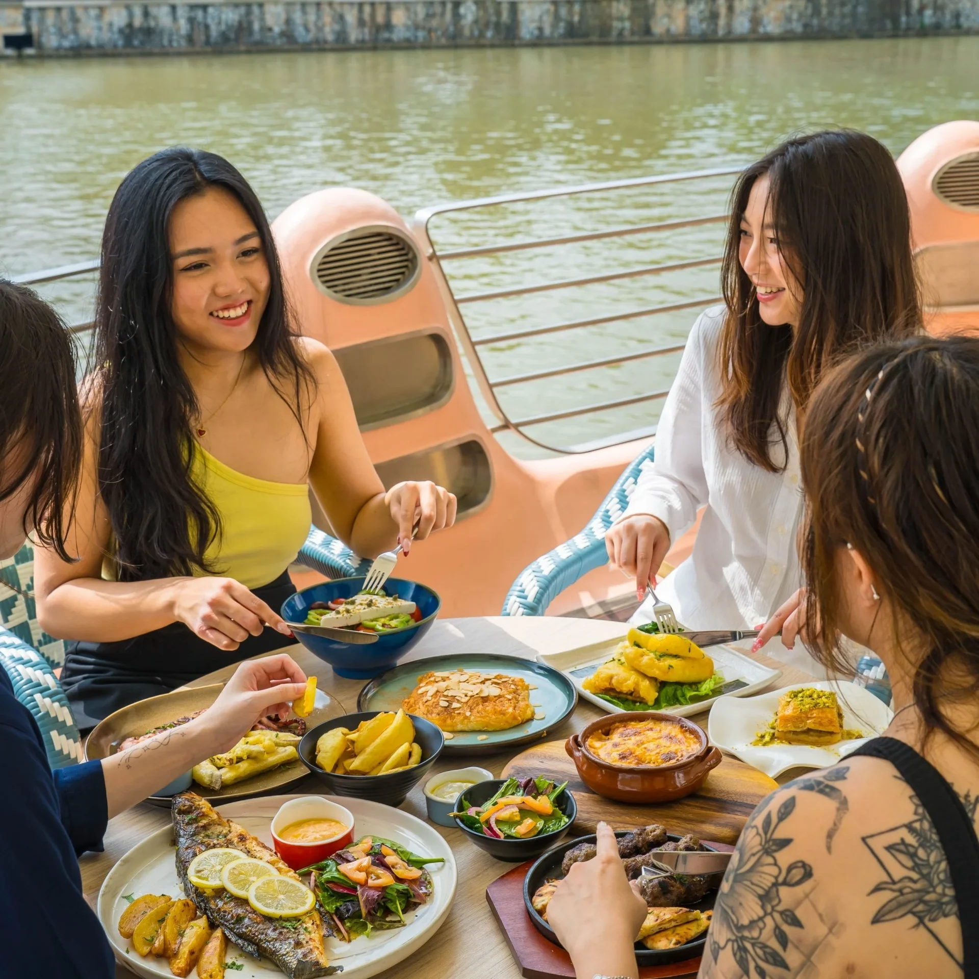 Friends sharing Greek dishes by the Singapore River at Zorba The Greek Taverna Clarke Quay